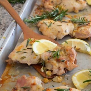 garlic lemon rosemary chicken thighs on sheet pan with spatula