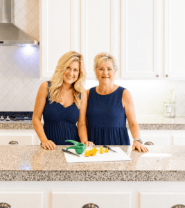 mother and daughter in a white kitchen in watching navy blue dresses