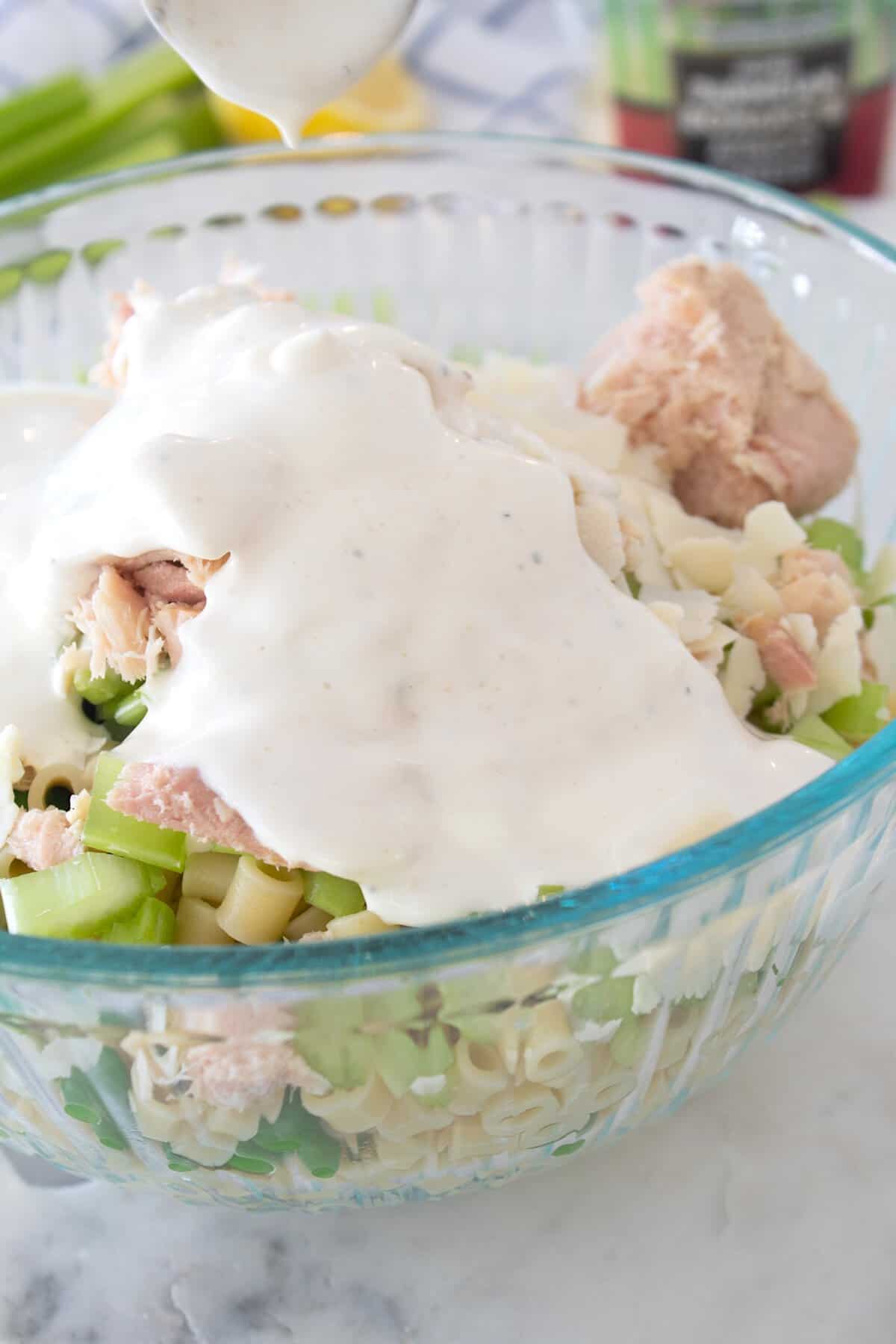 adding dressing to tuna pasta salad