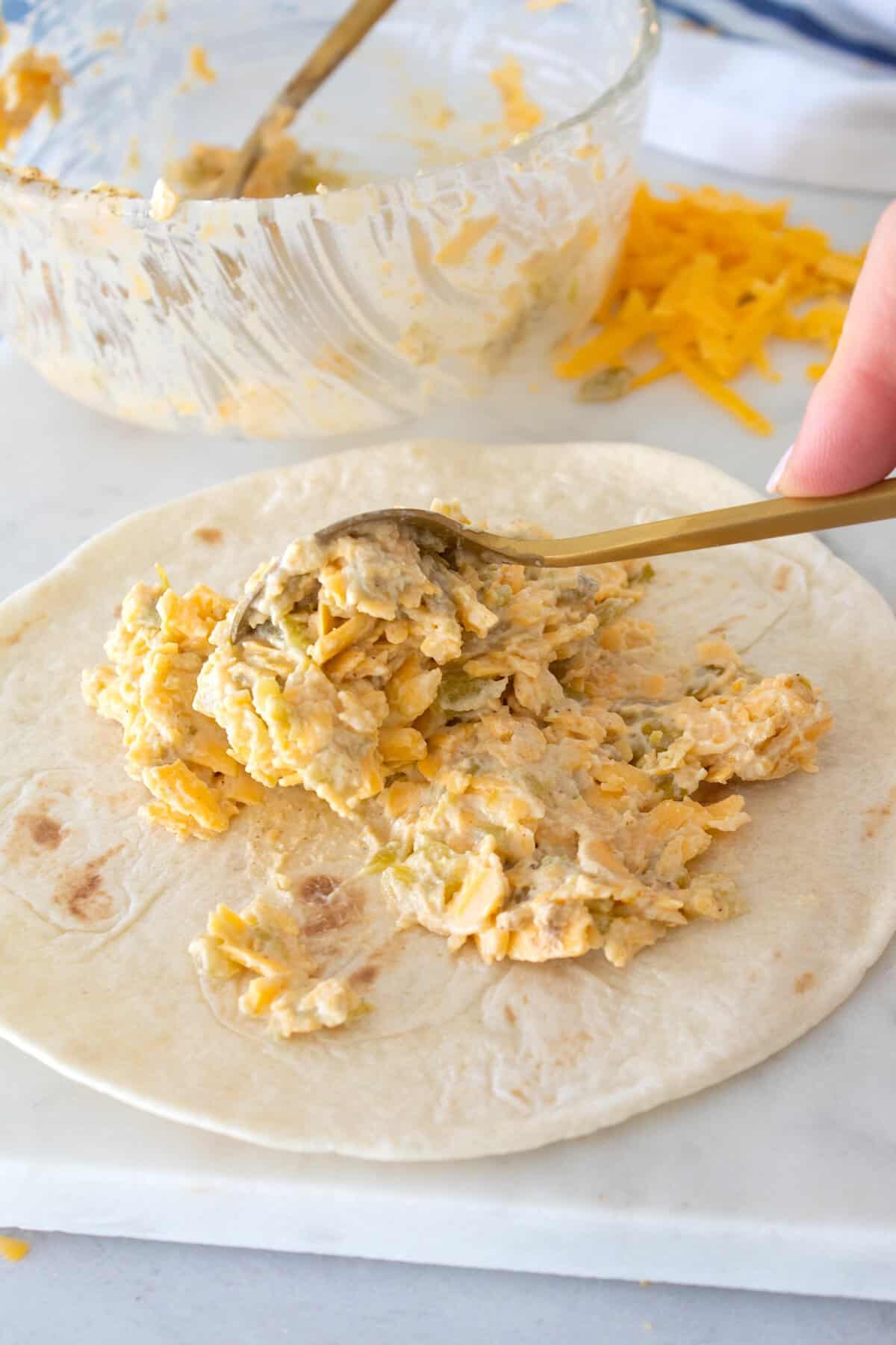 adding a spoonful of cheese mixture to a quesadilla