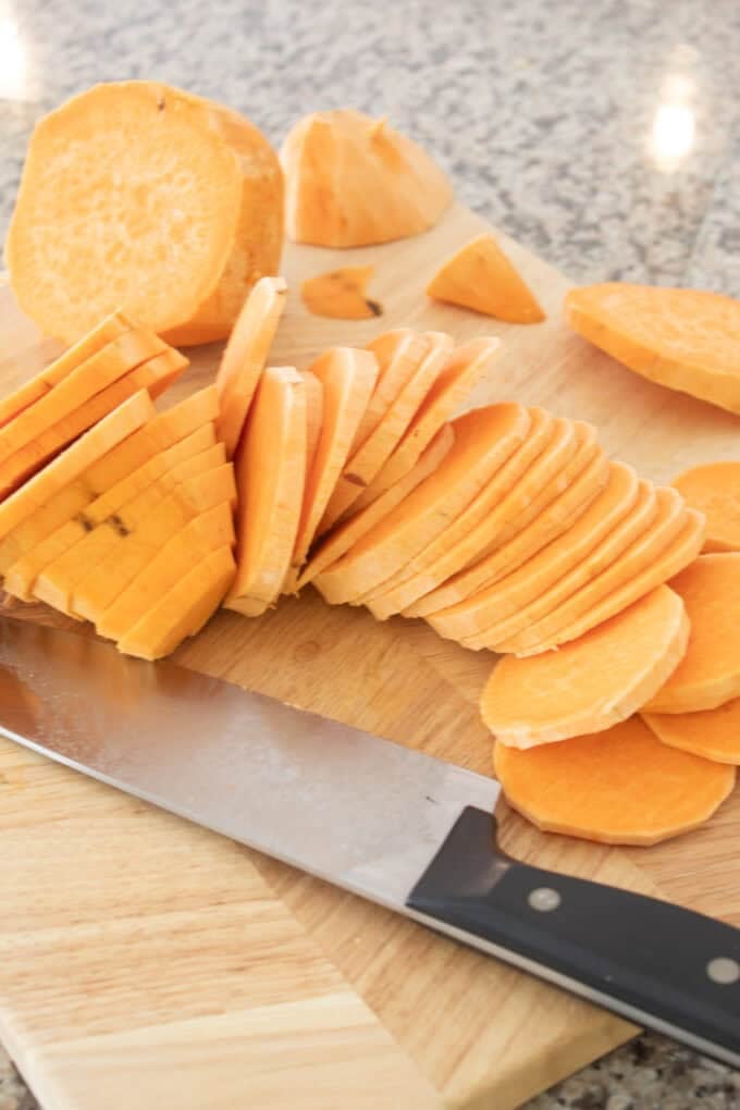 cutting sweet potatos into even slices on a cutting board