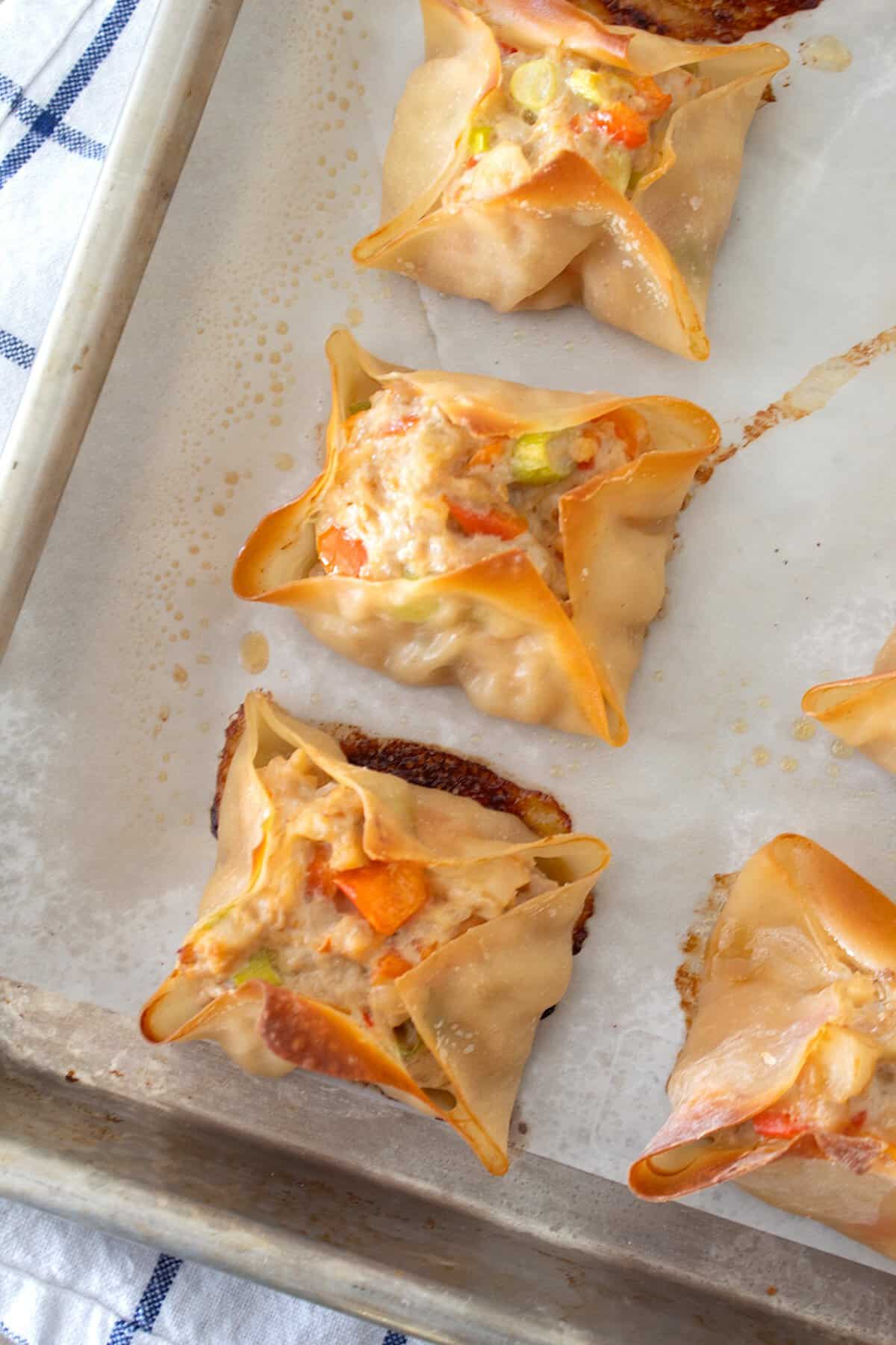 overhead view of baked chicken wontons on a cookie sheet