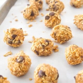 close up of peanut butter balls on a parchment lined sheet pan