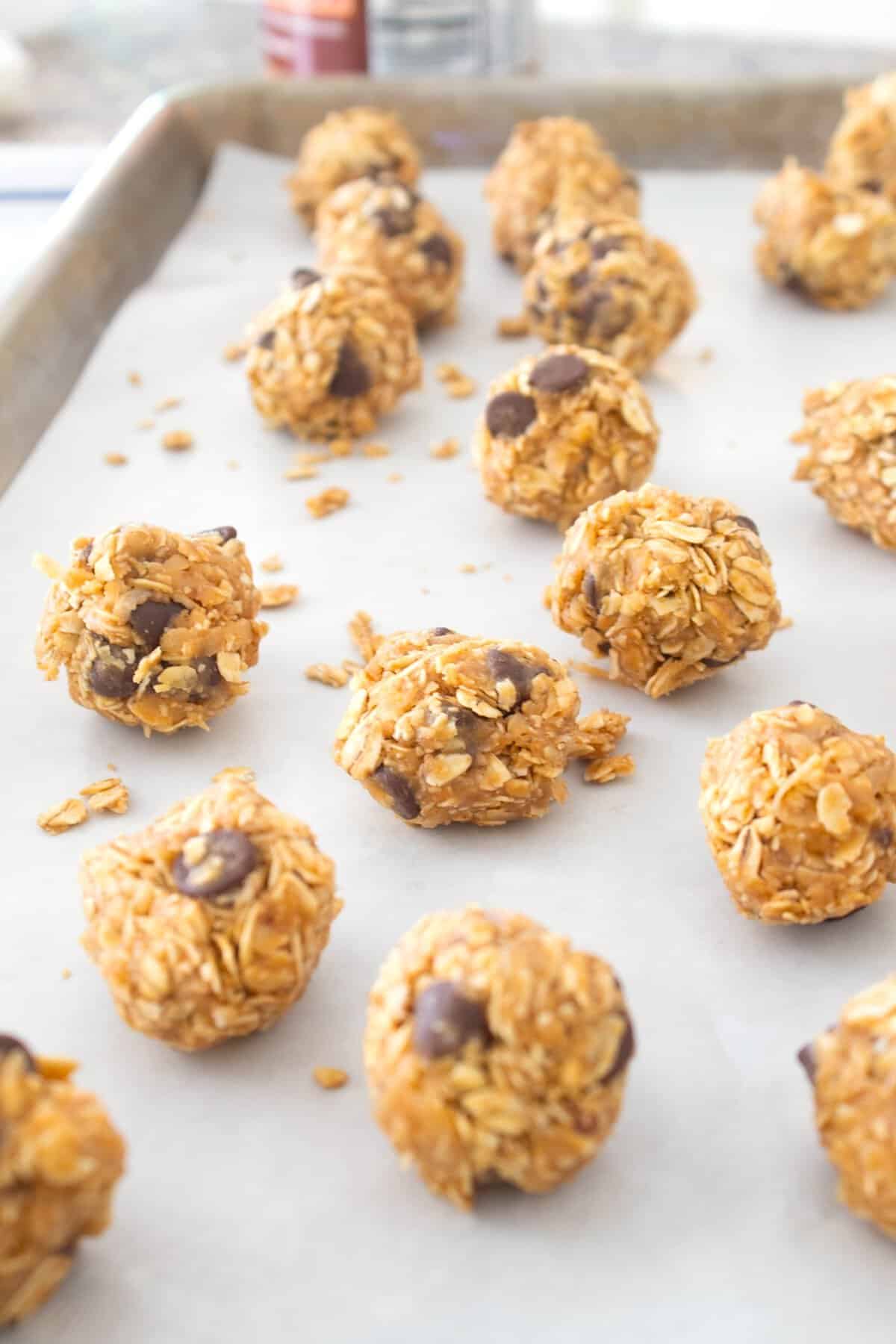 close up of peanut butter balls on a parchment lined sheet pan